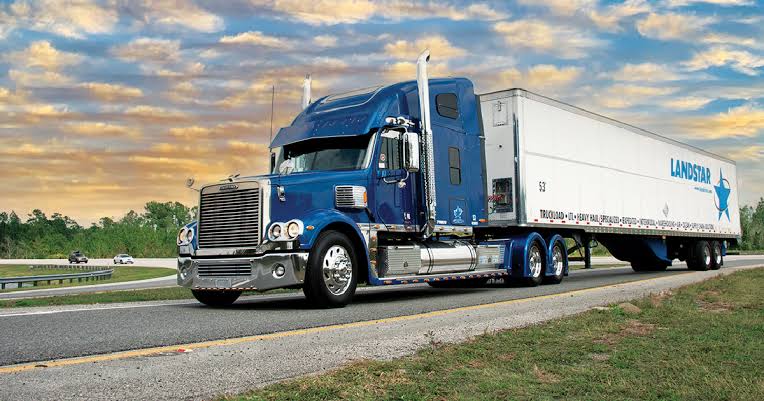 Blue Landstar semi-truck hauling a dry van trailer on a highway, representing Gwynn Logistics truckload capacity